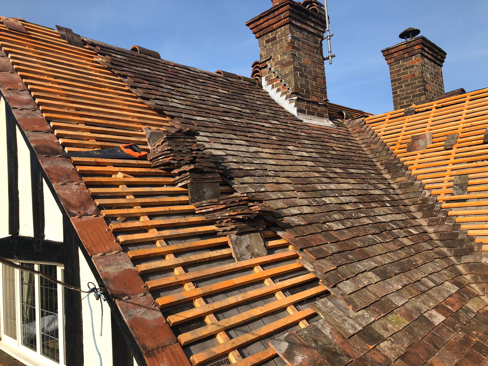 Roofer carrying out roof repair on pitched tiles